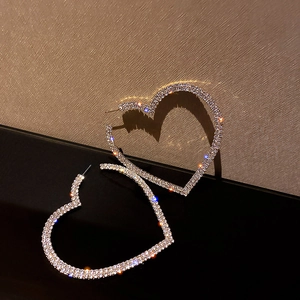 Macro shot of silver heart hoop earrings encrusted with sparkling rhinestones on stand