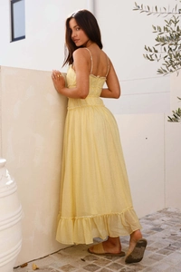 Détail de robe jaune à fines bretelles avec des couches de volants et mousseline plissée