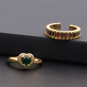Vue macro d'une bague coeur dorée avec pierre verte et gravure LOVE latérale