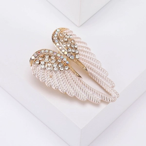Detail of angel wing brooch with pink enamel and sparkling rhinestones on gold base