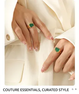 Détail de bagues vintage plaquées or 18 carats avec malachite verte portées sur un blazer blanc
