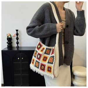 Detail of beige knit tote bag featuring colorful geometric squares and fringe accents