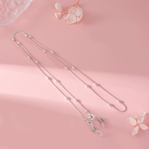 Macro detail of silver metal glasses chain with silicone loops on pink background
