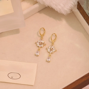 Detail of vintage gold drop earrings with floral design and zircons on a beige velvet tray
