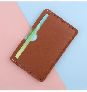 Close-up of brown leather slim card holder with white stitching and single card slot