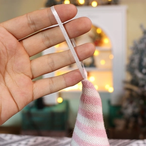 Close-up of pink and white striped knitted Christmas gnome ornament with hanging silk cord