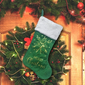 Green Christmas stocking with Merry Christmas print hanging on a rustic wooden door
