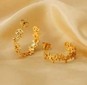 Detailed view of gold star hoop earrings on soft silk fabric with elegant metallic shine