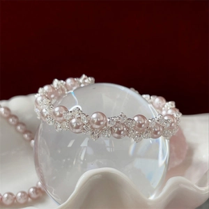 Detailed view of pink pearls and zircon woven bracelet on a decorative shell tray