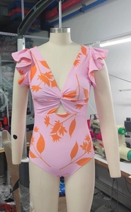 Dettaglio del costume intero rosa a fiori con scollo a V e maniche con volant