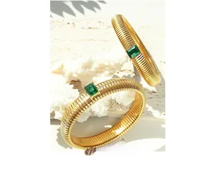 Detail of gold-plated bracelets with textured patterns and rectangular green zircon inlay