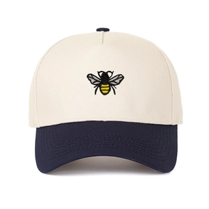 Detailed embroidery of a honey bee on a two-tone cream and navy trucker hat