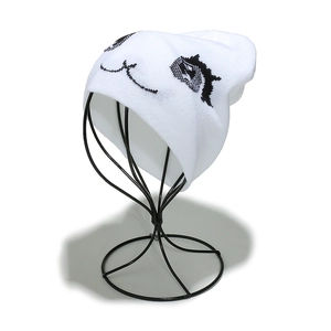 Détail du bonnet en tricot blanc avec motif d'yeux de dessin animé sur fond blanc