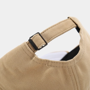 Close-up of beige cotton baseball cap with adjustable black metal buckle and twill fabric
