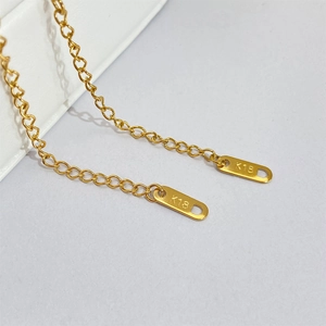 Detail shot of the 18K gold-plated oval pendant featuring the K18 engraving and fine chain