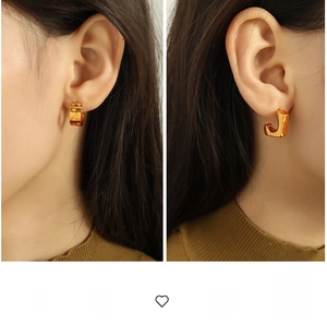Detail of 18k gold-plated C-shaped earrings with star patterns on a model