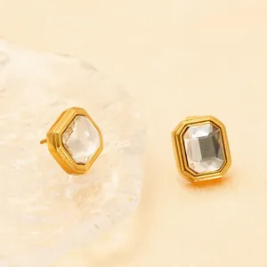 Octagon cut zircon stud earrings with gold plating on a decorative glass tray