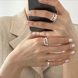 Close-up of knotted and twisted 925 sterling silver rings worn on hand with a beige blazer