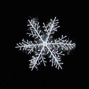 White iridescent Christmas snowflake ornament with laser laser film on black background