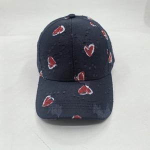 Detailed close-up of distressed black baseball cap with red heart graffiti patterns