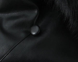 Détail d'une veste en cuir noir avec grand col en fourrure et boutons en cuir