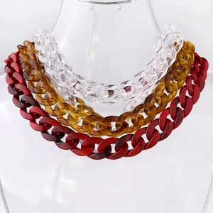 Detail view of bold acrylic chunky chain necklaces in clear, amber, and deep red colors