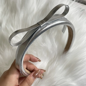 Silver metallic bow headband with PU leather texture on soft white faux fur background