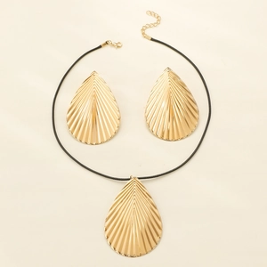 Macro detail of golden teardrop leaf jewelry set with radial texture on a white backdrop