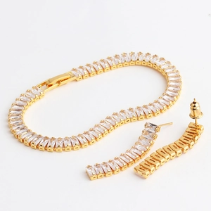 Macro detail of gold-plated bracelet and earrings set with baguette-cut zircon stones