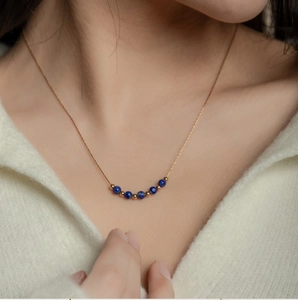 Dettaglio di perle di lapislazzuli e catena placcata oro 18K su una modella con maglione
