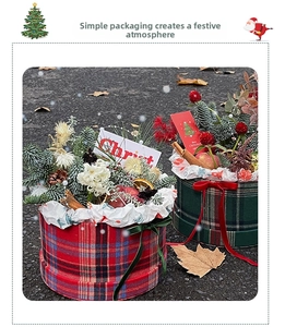 Outdoor shot of British plaid Christmas gift boxes with festive pine and apple decor