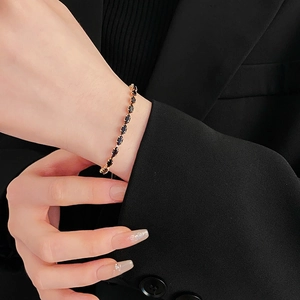 Close-up of elegant gold bracelet with marquise-cut black stones on woman's wrist