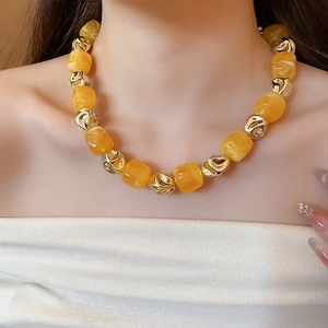 Close-up of chunky irregular yellow acrylic beads and gold metallic spheres on a necklace