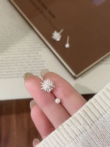 Macro view of asymmetric snowflake stud and small white pearl on a fingertip