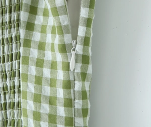 Detail view of invisible zipper and smocked green floral pattern fabric on side of dress