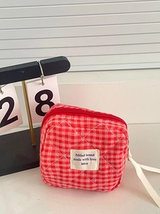 Detalle de bolsa acolchada a cuadros rojos y blancos con cremallera y textura suave