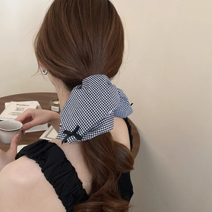 Black and white gingham bow scrunchie shown on brown hair in an elegant cafe setting