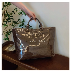 Detail showing high-gloss wrinkled texture of brown Tyvek tote bag with white text