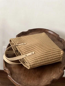 Macro shot of plaid tote bag with brown checkered pattern and leather handle details