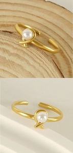 Detail of adjustable gold titanium ring with white pearl on natural wood and white steps
