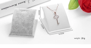 Gros plan d'un présentoir à bijoux en velours gris pour collier avec pendentif doré