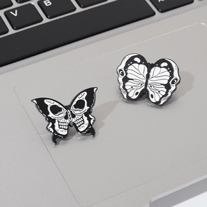 Detail view of skull moth enamel pins with black and white contrast on a laptop