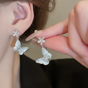 Close-up of elegant floral butterfly earrings with crystals and pearl texture on model
