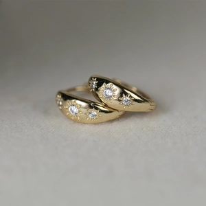Macro view of gold-plated silver hoop earrings with star-carved sparkling zircons