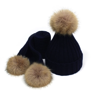 Detail showing high-quality dark blue knit hat and scarf set with brown faux fur pom poms