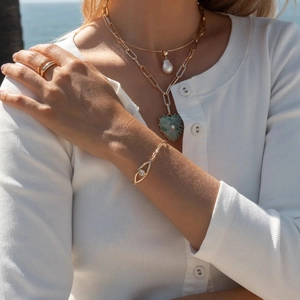 Close-up of 18K gold stainless steel layered necklace with green heart and pearl charms