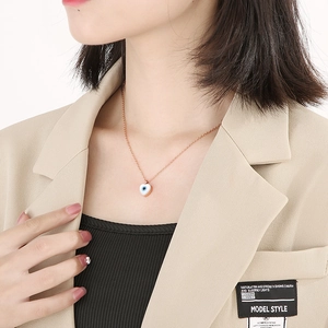 Close-up of heart-shaped evil eye pendant necklace in 18k gold plating on a model