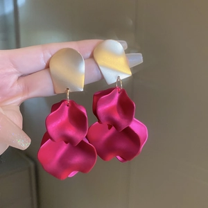 Detail of rose red leaf petal earrings with matte gold metallic geometric studs