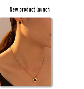 Close-up of a model wearing a gold and black heart-shaped necklace and earring jewelry set