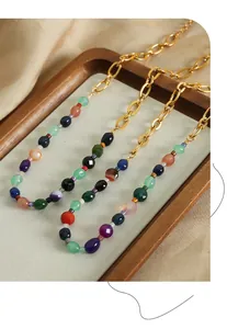 Détail macro de perles de pierres fines colorées et chaîne dorée sur plateau bois
